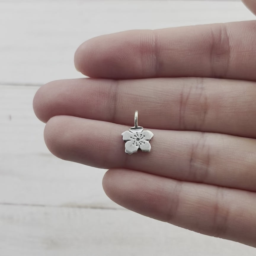 Tiny apple blossom charm, made from recycled sterling silver. Hand crafted in Marquette Michigan by Beth Millner jewelry using sustainable materials and practices.