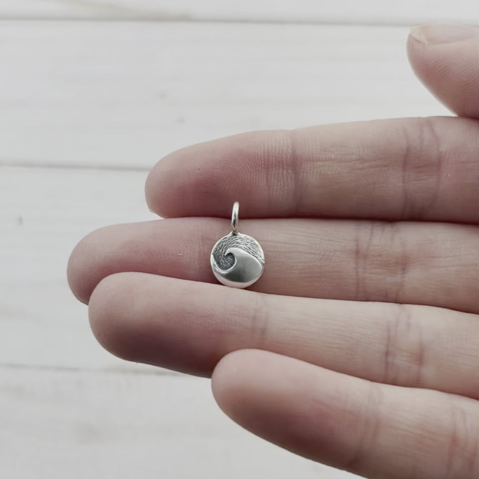 Tiny wave charm, made from recycled sterling silver. Hand crafted in Marquette Michigan by Beth Millner jewelry using sustainable materials and practices.
