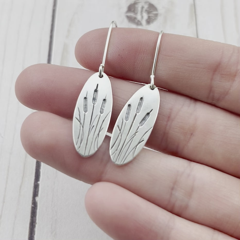 Oval sterling silver earrings featuring engraves cattails. By Beth Millner Jewelry.
