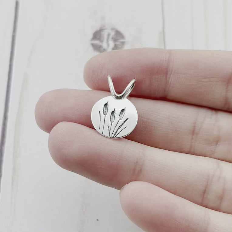 Round sterling silver pendant featuring engraved cattails. By Beth Millner Jewelry.