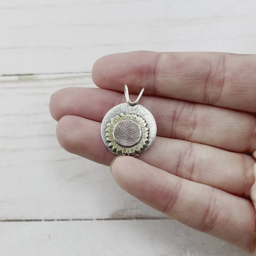 Round sterling silver pendant with a brass and copper sunflower. Handmade by Beth Millner Jewelry