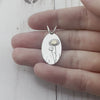 Oval sterling silver pendant featuring daisies with a yellow gold center. By Beth Millner Jewelry