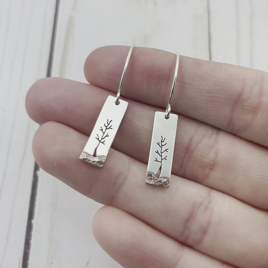 Rectangle sterling silver earrings featuring a hand sawn tree and copper landscape. By Beth Millner Jewelry.