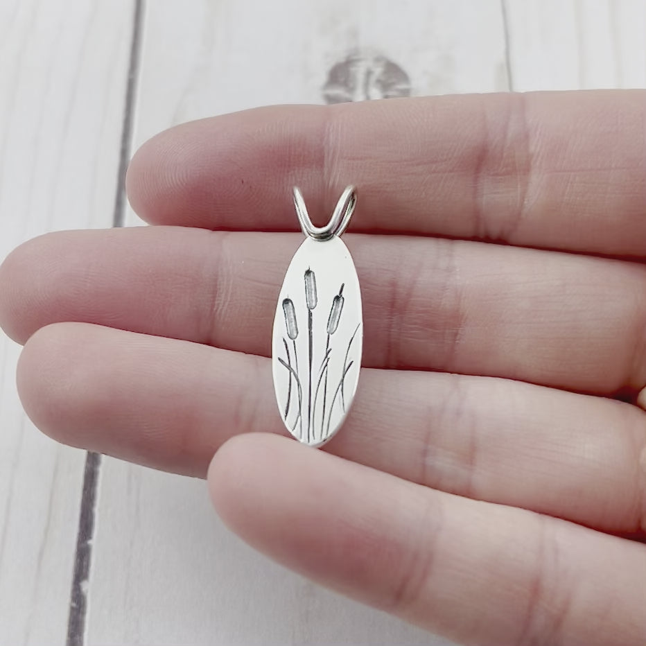 Oval sterling silver pendant featuring engraved cattails. By Beth Millner Jewelry. 